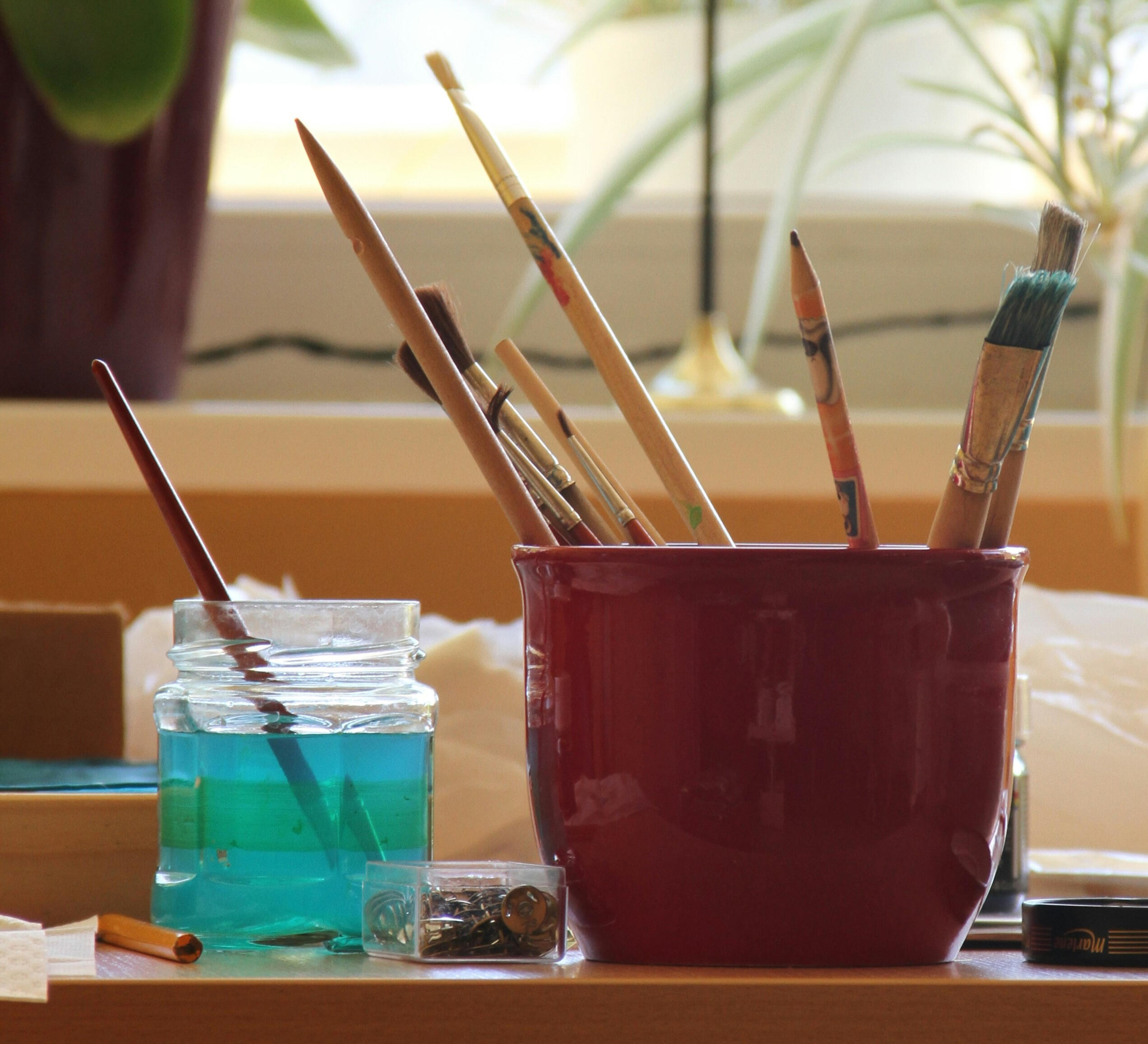 Kyniä ja siveltimiä purkissa ikkunalaudalla.